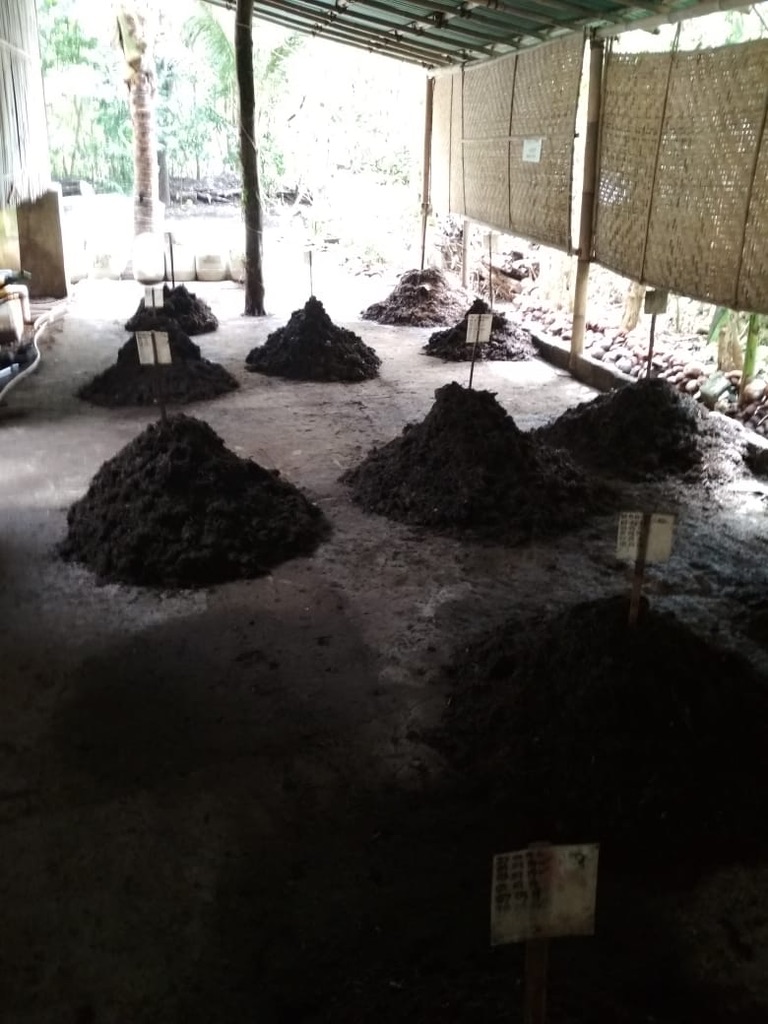Multiple labelled compost piles under a covered outdoor structure