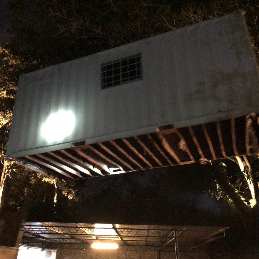 Image 35. Elevated white shipping container with exterior lighting at night