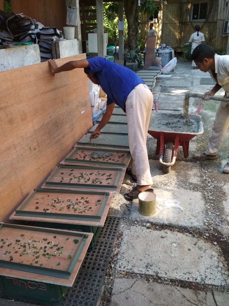 Workers casting glass-aggregate tiles with green glass chips