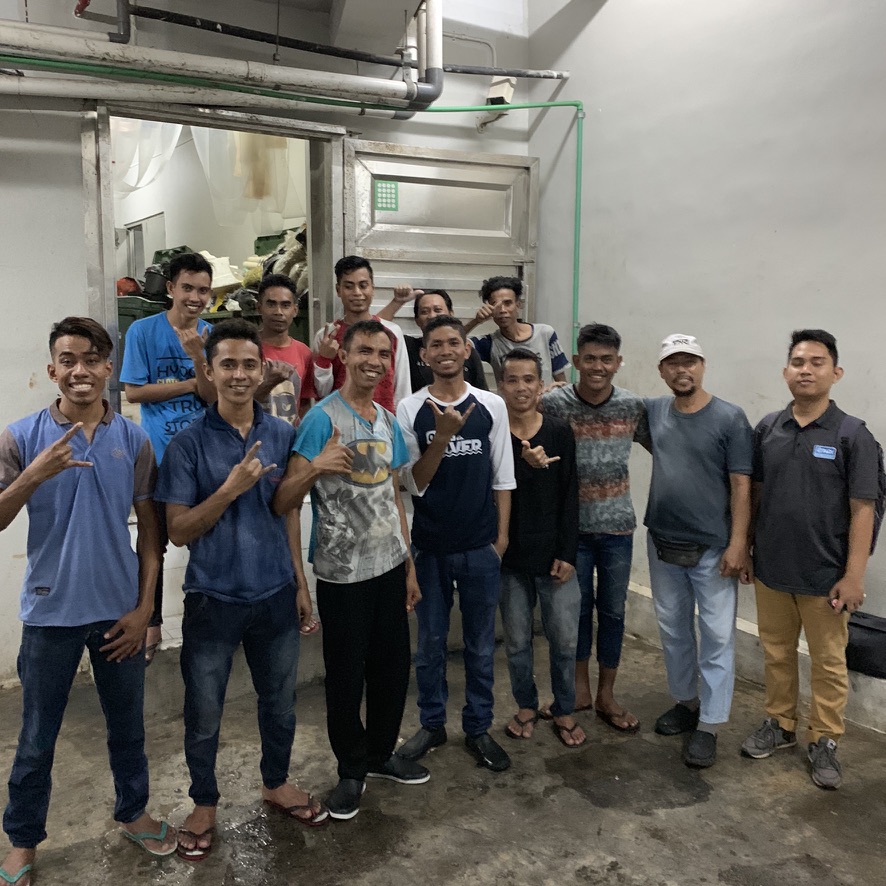 Large group of smiling recovery operators posed together in an indoor work area