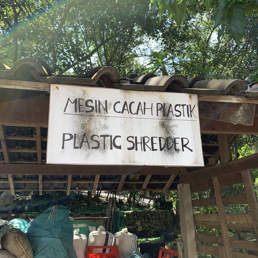 Image 36. Hand-painted sign Mesin Cacah Plastik Plastic Shredder above a covered bay