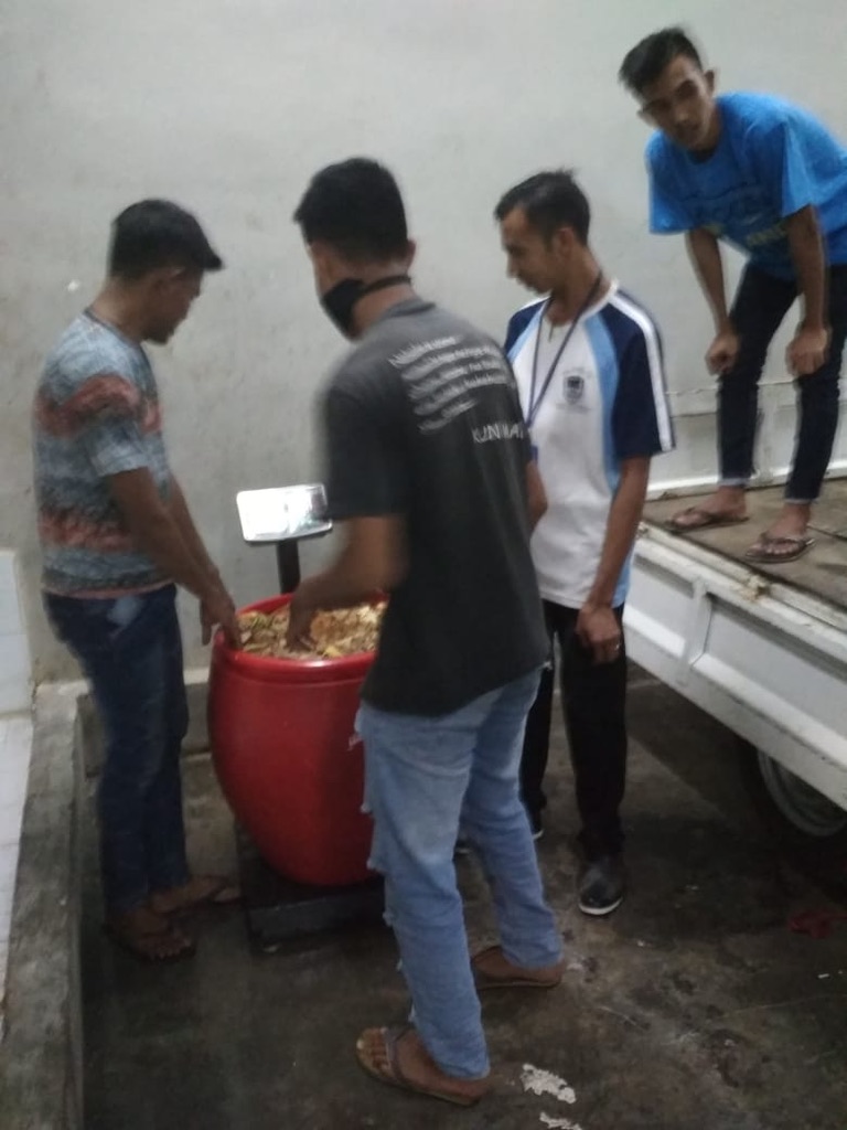 Image 16. Team weighing a large red tub of organic material on a floor scale