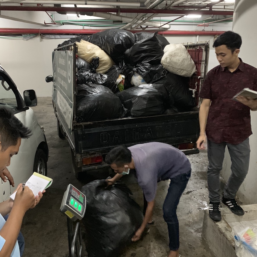 Team weighing bags on a floor scale while a loaded truck waits nearby