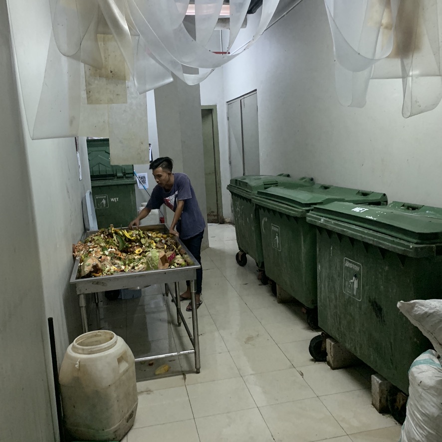Image 13. Person sorting wet organics on a metal table beside green wet bins